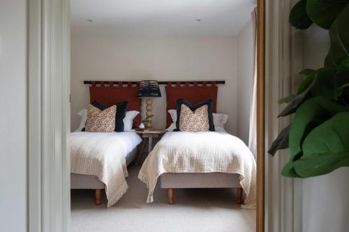 a bedroom with two beds with white blankets and pillows at Willowbrook House- A luxurious countryside retreat set in an idyllic & desirable location close to Soho Farmhouse and lots of Cotswold attractions - Dogs welcome in Kiddington