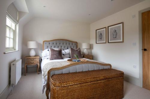 a bedroom with a large bed with a brown ottoman at Willowbrook House- A luxurious countryside retreat set in an idyllic & desirable location close to Soho Farmhouse and lots of Cotswold attractions - Dogs welcome in Kiddington