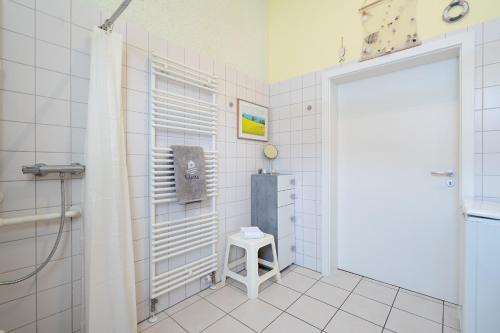 a bathroom with a shower and a stool next to a door at Feriendorf Südstrand Haus 18 in Pelzerhaken