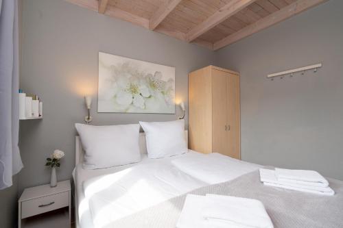 a bedroom with a large white bed with white pillows at Feriendorf Südstrand Haus 18 in Pelzerhaken