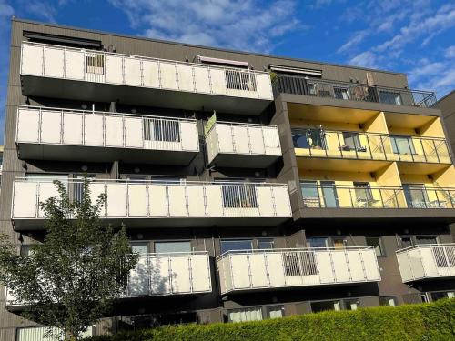 an apartment building with white balconies and a tree at Nice apartment in modern complex near Old Bergen in Bergen