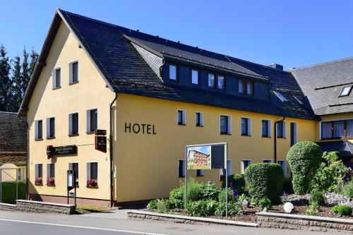 CursdorfにあるHotel Im Kräutergartenの通り沿いにある大きな黄色いホテル