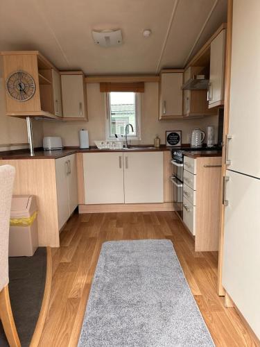 a small kitchen with white cabinets and a rug at Swift Moselle 2 Bedroom Caravan Located in Uddingston, Glasgow at Maryville Caravan Site in Uddingston
