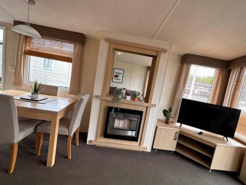 a living room with a dining table and a television at Swift Moselle 2 Bedroom Caravan Located in Uddingston, Glasgow at Maryville Caravan Site in Uddingston
