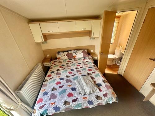 a small bedroom with a bed with a quilt on it at Swift Moselle 2 Bedroom Caravan Located in Uddingston, Glasgow at Maryville Caravan Site in Uddingston