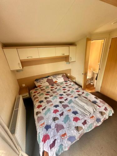 a small bedroom with a bed with a quilt on it at Swift Moselle 2 Bedroom Caravan Located in Uddingston, Glasgow at Maryville Caravan Site in Uddingston