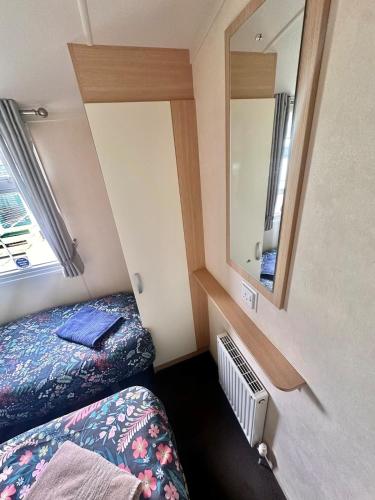 a small room with a bed and a mirror at Swift Moselle 2 Bedroom Caravan Located in Uddingston, Glasgow at Maryville Caravan Site in Uddingston