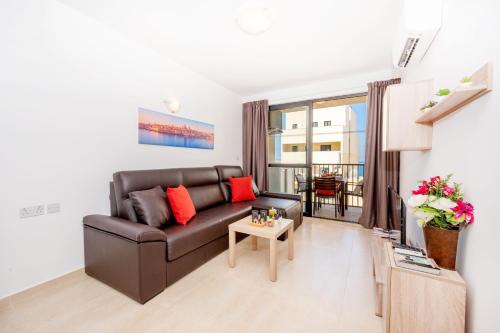 a living room with a couch and a table at Sea Bliss Apartments with terrace just off seafront in St Paul's Bay - By Getawaysmalta in St. Paul's Bay