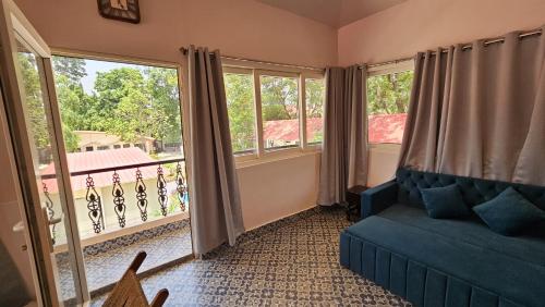 a living room with a couch and large windows at SANTINIKETAN RETREAT, Bolpur in Shānti Niketan