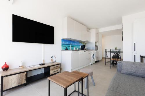 un salon avec une télévision sur un mur blanc dans l'établissement Immogroom - t2 new - bright - fully equipped, à Cannes