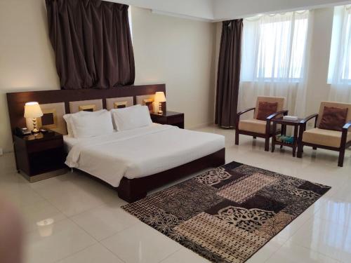 a bedroom with a large bed and two chairs at منتجع شاطئ الدولفين للإيواء السياحي in Yanbu