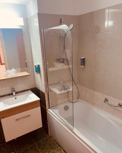 a bathroom with a shower and a tub and a sink at Hotel Moldova in Bîrlad