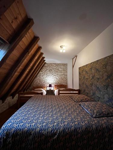 une chambre avec un lit et un mur en pierre dans l'établissement Moulin du grand auque, à Lalandusse