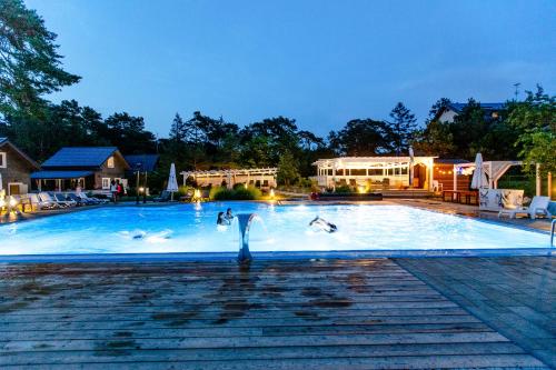 a swimming pool with swans on it at night at OŚRODEK KOLONIJNO WCZASOWY MEWA - przy plaży z basenem z podgrzewaną wodą i mini SPA in Niechorze