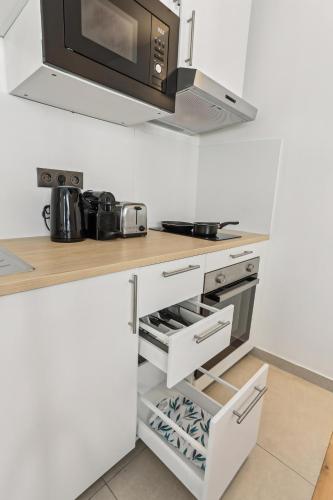 - une cuisine avec un comptoir blanc et un four micro-ondes dans l'établissement Appartement charmant proche de la Défense, à Puteaux