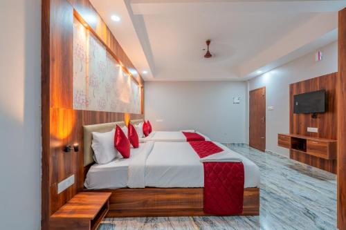 a bedroom with a bed with red pillows and a television at Daan Residency Near Karukapilly Kaloor Palarivattom in Ernakulam