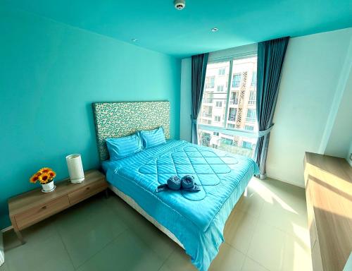 een blauwe slaapkamer met een bed met schoenen erop bij Better Homes at Atlantis Condo Resort in Jomtien Beach