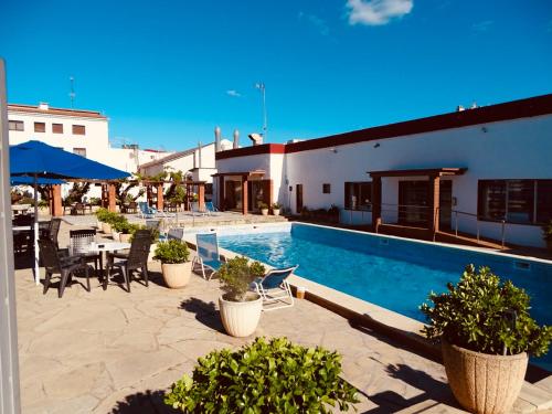 a swimming pool with chairs and a table and a building at Hostal Lleida in Segur de Calafell