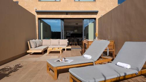 un patio avec deux chaises longues et un canapé dans l'établissement ASTER spa & beach dúplex, à La Vila Joiosa