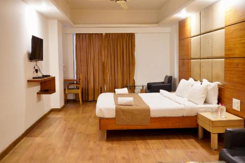 a hotel room with a bed and a television at The Sky Comfort, Ahmedabad in Ahmedabad