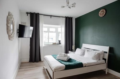 a bedroom with a bed with a green wall at City Gate Guest House in London