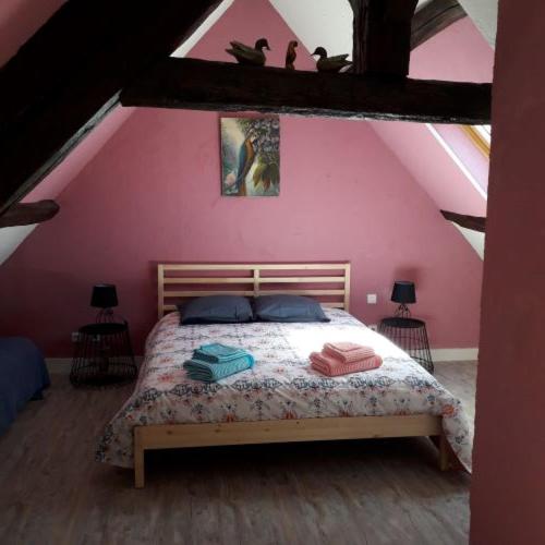 une chambre avec un lit dans un mur rose dans l'établissement Le Grand Gîte de Beauval, à Mareuil-sur-Cher