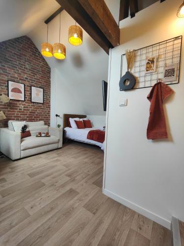 a living room with a white refrigerator and a couch at Les Briques Rouges, Appartement Béthune in Béthune