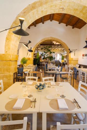 a restaurant with white tables and chairs and a brick wall at Baglio Siciliamo Country House in Noto Marina