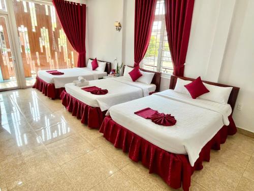 three beds in a room with red curtains at OPA HOTEL HUE in Hue