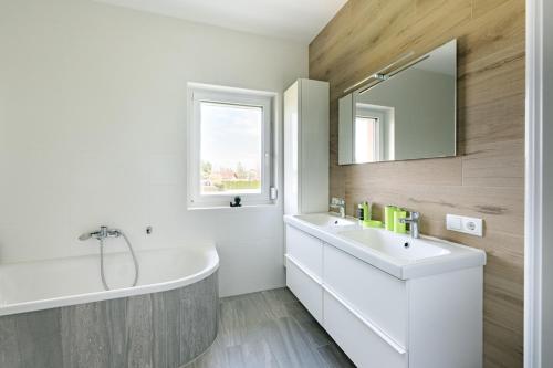 a white bathroom with a tub and a sink at TAMLiving Südsteiermark in Obergralla