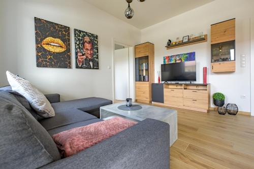 a living room with a couch and a tv at TAMLiving Südsteiermark in Obergralla