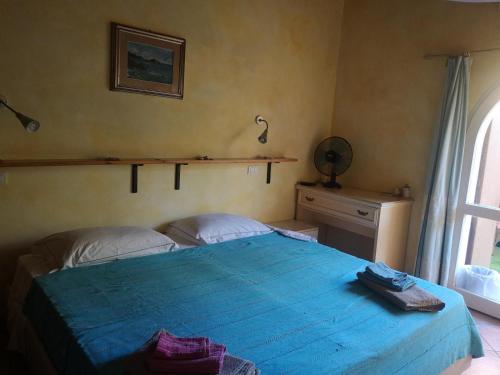 a bedroom with a blue bed and a window at Casa Valeria in Teulada