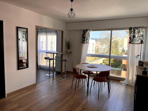 un salon avec une table et des chaises et une fenêtre dans l'établissement Bel appartement cosy Chartres, à Chartres