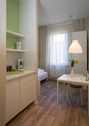 a kitchen with a table and a room with a bed at GuestHouse Köhn51, zentral gelegene, stilvoll eingerichtete Zimmer mit eigener Teeküche in Nürnberg