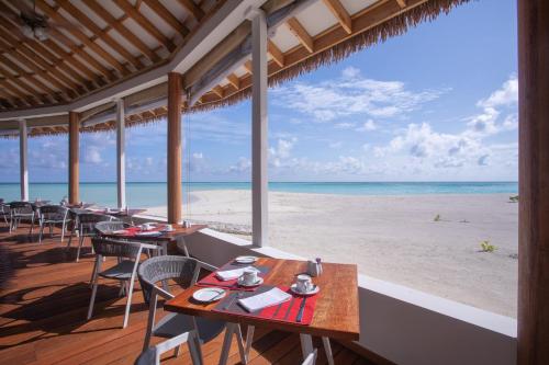 a restaurant with tables and chairs on the beach at Cinnamon Velifushi Maldives in Keyodhoo
