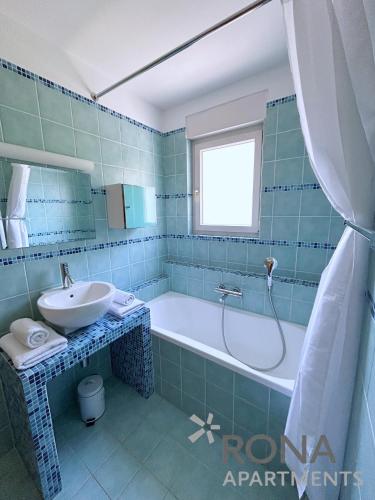 a blue tiled bathroom with a tub and a sink at Rona Spacious apartment with a panoramic view in Ičići