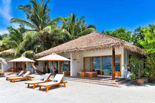 a group of lounge chairs and umbrellas on a beach at Cinnamon Dhonveli Maldives in North Male Atoll