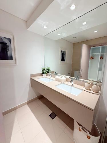a bathroom with two sinks and a large mirror at 2 Bedroom In Waters Edge Voyage in Yas Island