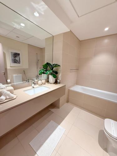 a bathroom with a sink and a tub and a toilet at 2 Bedroom In Waters Edge Voyage in Yas Island