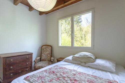 a bedroom with a bed and a chair and a window at Chalet de Gretteguerre in Lanne en Barétous