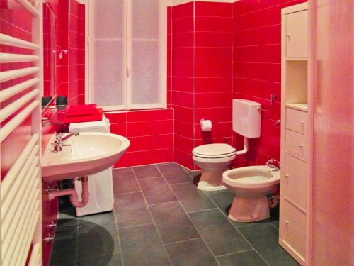 a red bathroom with a toilet and a sink at Palazzina GiardinoLago in Gravedona