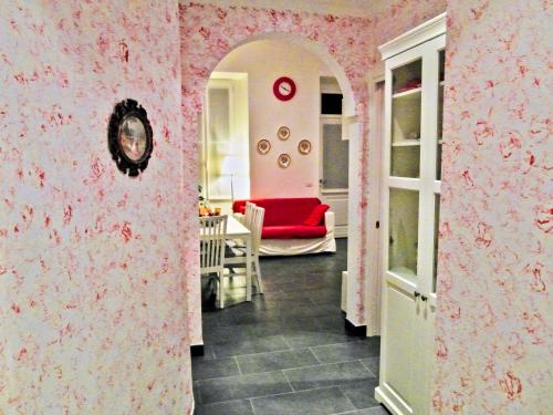 a living room with pink wallpaper and a red couch at Palazzina GiardinoLago in Gravedona