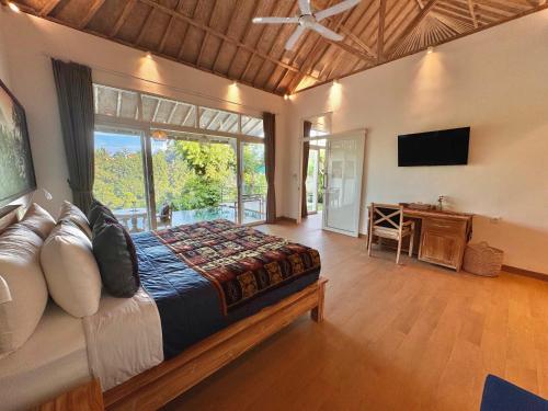 a bedroom with a large bed and a television at Suara Jiwa Luxury Villas with Private Pool in Ubud