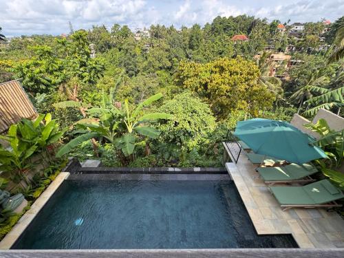 a swimming pool with two chairs and an umbrella at Suara Jiwa Luxury Villas with Private Pool in Ubud