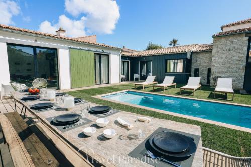 un patio avec une table à côté d'une piscine dans l'établissement ILE DE RE - Villa Clerjotte, à Saint-Martin-de-Ré