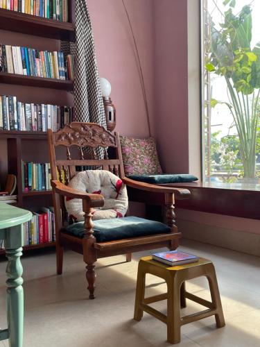 a room with a chair and a book shelf at Here Library - A wooden home by the river with a library in Thốt Nốt