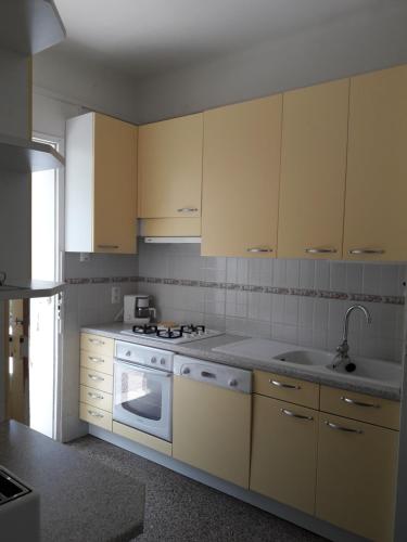 une cuisine avec des appareils électroménagers blancs et des armoires jaunes dans l'établissement T3 jardin, parking, terrasse à 80 m de la plage à Saint cyr sur mer, aux Lecques