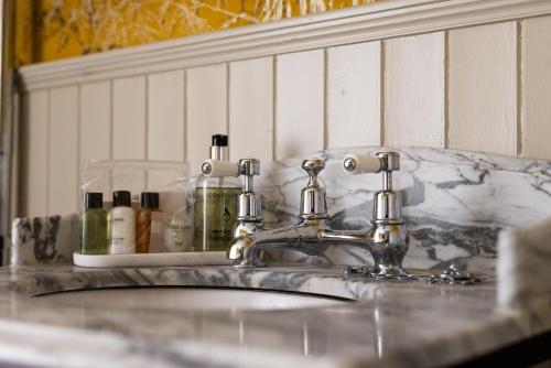a bathroom sink with two faucets and bottles on it at Greta Howe in Keswick