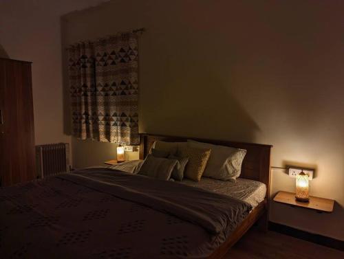 a bedroom with a bed with two lamps and a window at Bagaan - Tea Plantation Stay, Ooty in Aruvankadu