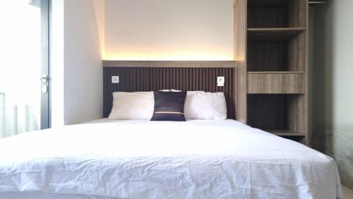 a bedroom with a white bed with a wooden headboard at Dancenter Bekasi Formerly Riverdale in Tanahbaru